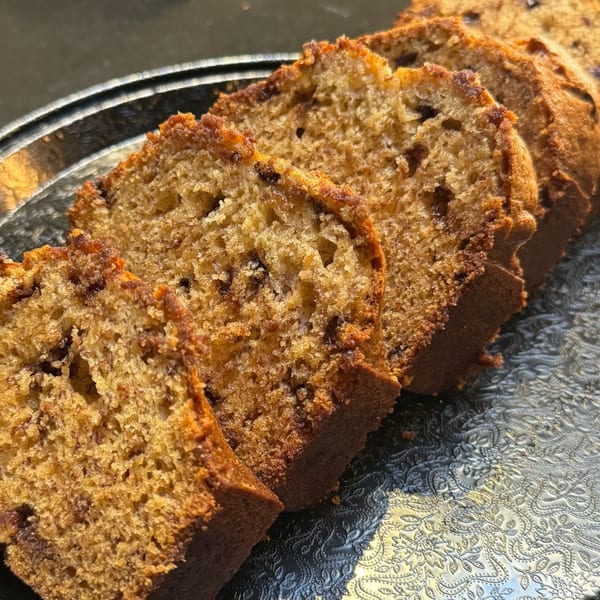 Slices of banana bread with chocolate chips on a decorative silver tray.