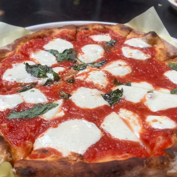 Close-up of a Cali-Forno Pizzeria Margherita pizza with fresh mozzarella, tomato sauce, and basil.