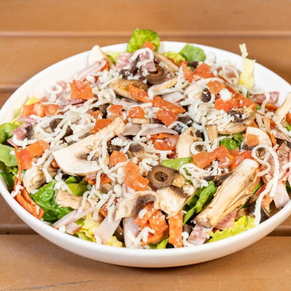 A large Cali-Forno Pizzeria salad with greens, mushrooms, tomatoes, olives, and shredded cheese.